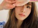 A woman with long brown hair holding her head in her hands.