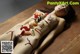 A naked woman laying on a wooden table covered in sushi.