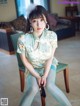 A woman sitting on a chair wearing a green dress and stockings.