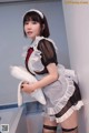 A woman dressed as a maid holding a pillow.