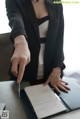 A woman in a business suit holding a pen and signing a document.