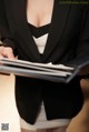 A woman in a black suit holding a folder.