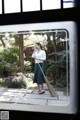 A woman standing in front of a window holding a broom.